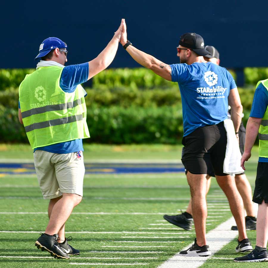 STARability participant and volunteer high-fiving on football field | Volunteer STARability Foundation