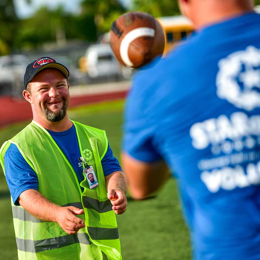 STARability participant and volunteer playing catch with football | Volunteer STARability Foundation