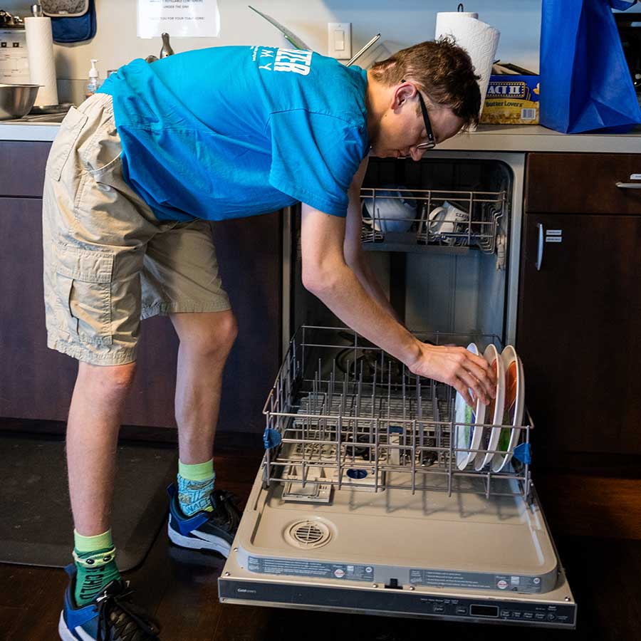 STARability participant filling dishwasher | Cooking Class STARability Foundation