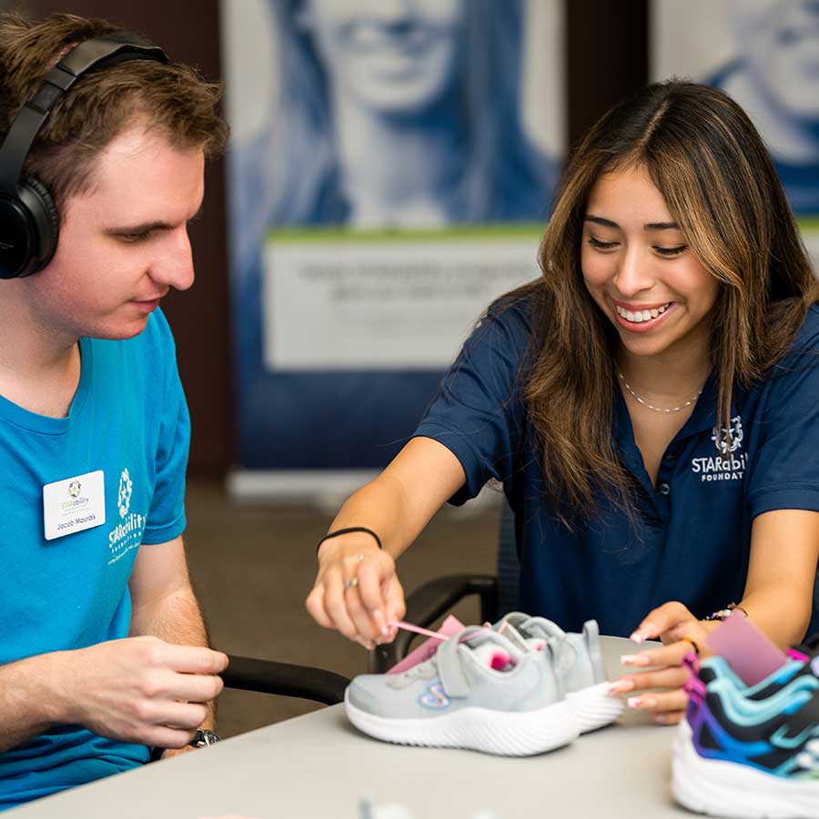 Instructor teaching STAR participant how to tie shoe laces | STARability Foundation